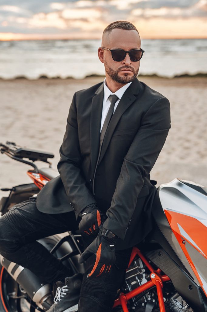 Cool guy with sunglasses and dark motorcycle on beach